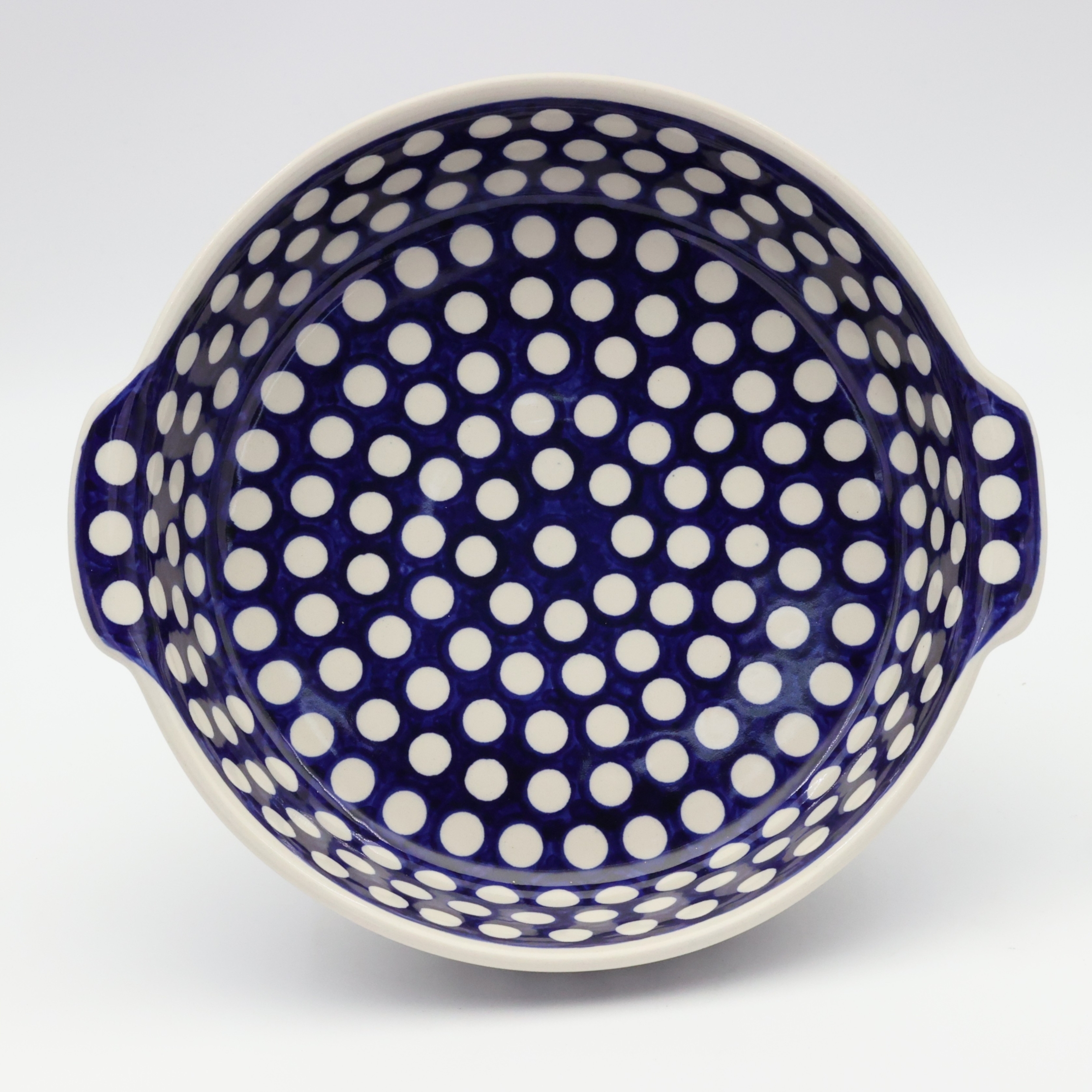Round ceramic serving dish with handles – Bolesławiec pottery, hand-decorated with traditional patterns. Perfect for serving meats, salads, and appetizers. Stylish and durable Polish ceramic.